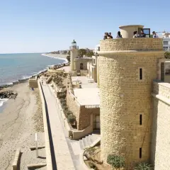 Torreón y faro en el **puerto de Roquetas de Mar**, con playa y mar Mediterráneo al fondo.